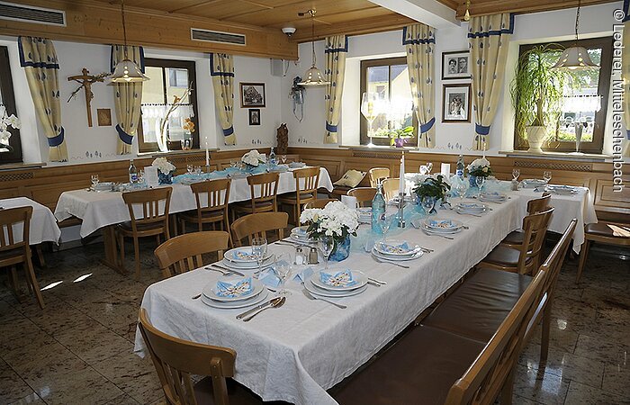 Gasthof "Zur Krone" Ein gedeckter Tisch im Saal vom Gasthof Lederer. In zwei Reihen bestuhlte Tische mit Stühlen. Darauf weiße Tischdecken und Gedeck.