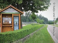 Unser Hofladen in Bammersdorf Links ein 24-Stunden-Selbstbedienungshofladen. Rechts davon eine kleine grüne HEcke. Daneben verläuft eine Straße.